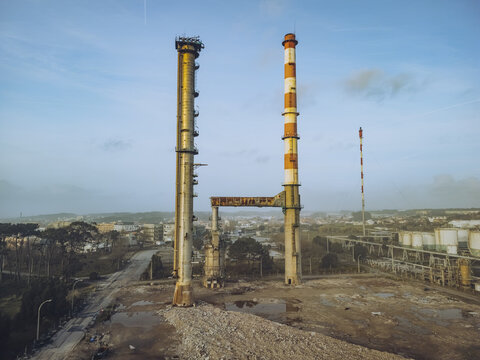 Aerial view of industrial chimneys piercing the skyline with their weathered textures and faded colors, contrasting against the urban sprawl, Matosinhos, Portugal.