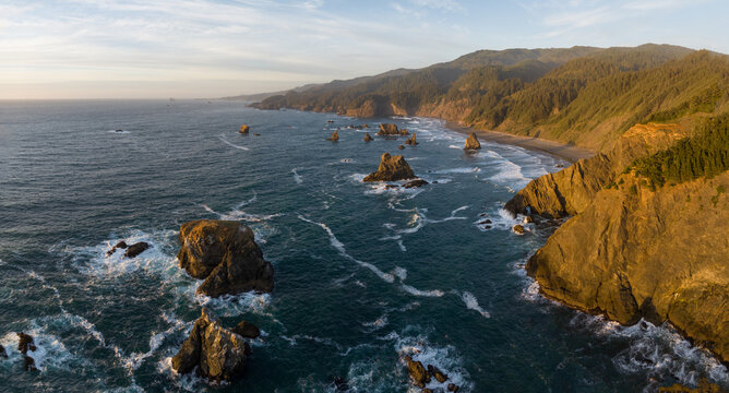 Aerial view of jagged cliffs meet the turbulent ocean, where rocky stacks stand defiant against the relentless waves, Brookings, Oregon, United States.