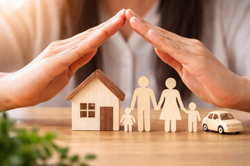 Person holding hands over house and family next to car representing protection