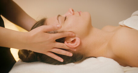 Fototapeta premium Happy Young Woman Lying on Bed at Spa Salon and Enjoying Back Massage. Cosmetologist Massaging Female Client Back and Neck for Lymphatic Drainage and Lifting Effect. Beauty, Skin Care Concept