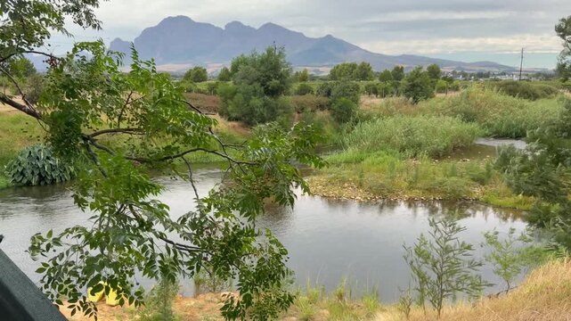 A river nestled in a valley with mountains in the background. The Berg River in Paarl area near Cape Town, South Africa.