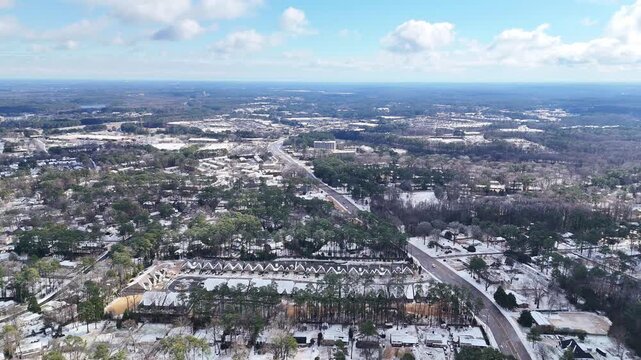 Snowy suburban neighborhood with trees and roads under blue sky, Cary, North Carolina, USA