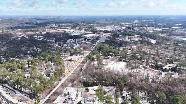 Snowy suburban landscape with trees and houses under blue sky, Cary, North Carolina, USA