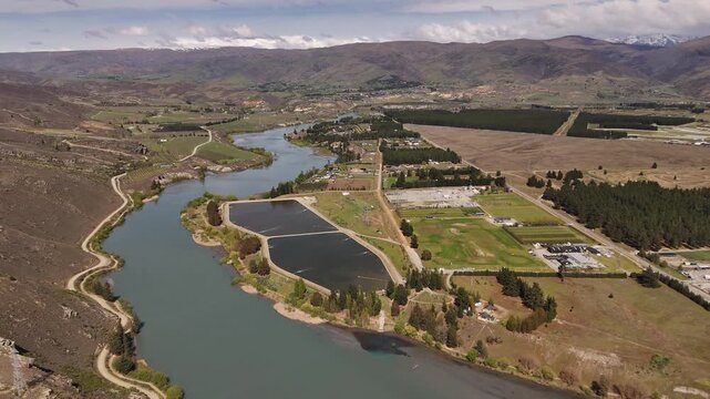 Cinematic 4K 60fps drone flyover showcasing the residential suburbs of Cromwell town situated along the banks of the blue Clutha River in the Central Otago region