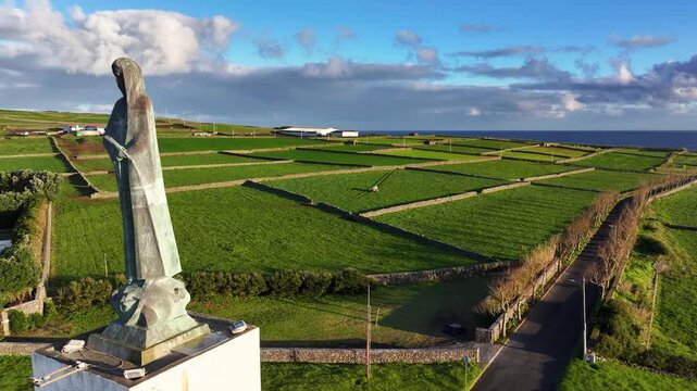 Serra do Facho viewpoint with bronze statue near lush Terceira pastures, aerial