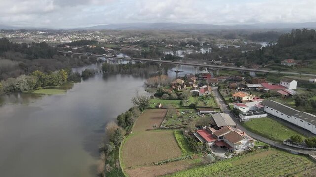 Overhead perspective reveals muddy floodwater spreading through rural zones, isolating small patches of higher ground. Drone moving forward over the overfilled river.