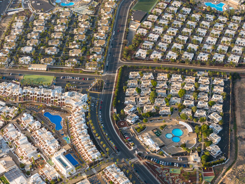 Aerial view of uniform white villas bask in the warm sunlight, their rooftops creating a geometric tapestry above the landscape, Playa Blanca, Lanzarote, Canary Islands.