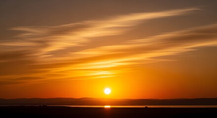 Golden sunset horizon over calm water with streaky clouds