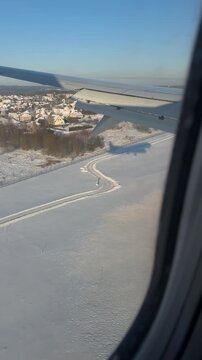 Aerial view of snowy village with airplane shadow visible landing in Kaunas Airport, Lithuania