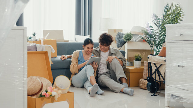 Young happy Asia couple sit on sofa couch use digital tablet online shopping furniture from decoration store in living room at home. Husband wife move new house, Apartment Rent And Ownership Concept.