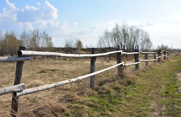 Rustic Wooden Fence in a Dry spring Field with sunlight