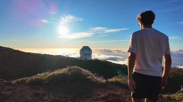 Slow motion footage of person walking toward telescope above clouds at Roque de los Muchachos, La Palma