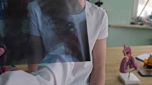 Medical professional examines chest X-ray while patient looks on in a clinical setting