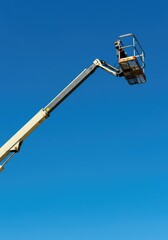 A heavy duty motorized aerial work platform, known as a cherry picker, extending its hydraulic boom high up toward the clear blue sky ,engine ,extended ,large