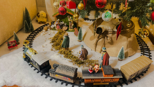 Nativity scene next to the Christmas tree, with train, wise men, decorative trees, sheep and reindeer