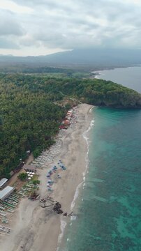 4K drone video flying away from Song Lambung Beach in Nusa Lembongan near Bali in Indonesia. This stunning white sand beach is a popular spot for tourists looking to relax and surf.