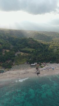 4K drone video flying away from Song Lambung Beach in Nusa Lembongan near Bali in Indonesia. This stunning white sand beach is a popular spot for tourists looking to relax and surf.