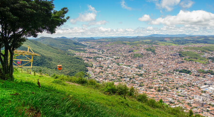 Panoramic view over city of Pocos de Caldas, Minas Gerais, Brazil, and cable car gondola descending towards city © Caio