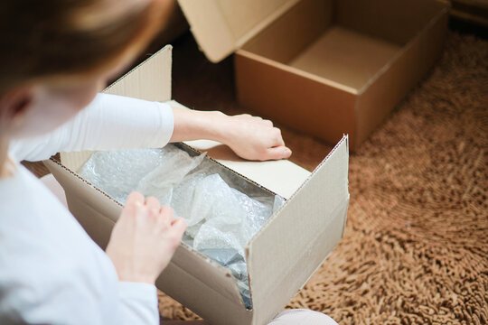Receiving and unpacking orders. Woman in white unpackes the cartoon boxes with clothes at home.  Delivery. Cartoon packages unpacking. 