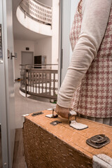 Woman's hand holding a retro suitcase, walking through a doorway, leaving a contemporary residential or office building