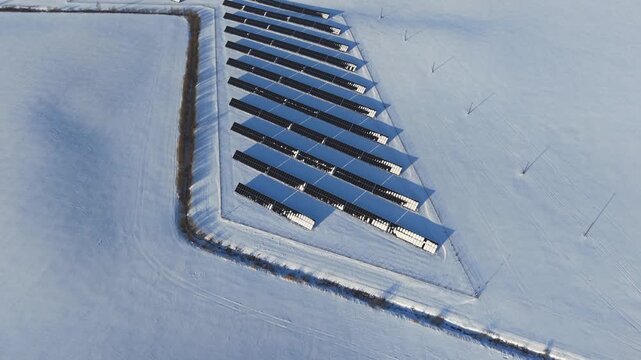 Solar panels partially covered with snow during cold winter conditions, aerial overview, thin column