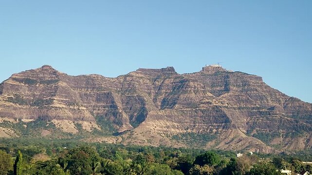 Pavagadh hill mountain landscape near Champaner Gujarat India. Rocky cliffs and green forest at foothills under clear blue sky, popular heritage and pilgrimage destination in western India.