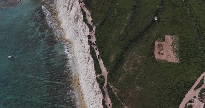 Aerial view of the dramatic white cliffs meeting the turquoise sea, with a winding path along the cliff edge, Munxar Path, Marsaskala, Malta.