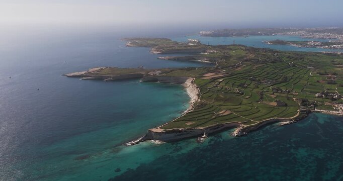 Aerial view of the Munxar Path coastline, where the turquoise sea meets the green fields, creating a stunning visual contrast, Marsaskala, Malta.