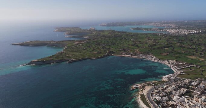 Aerial view of the rugged Munxar Path coastline where the turquoise sea meets the verdant landscape and the built environment, Munxar Path, Marsaskala, Malta.