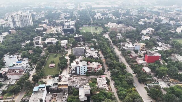 Aerial footage of the Indian flag commands the skyline in the distance of this peaceful park setting, framed by geometric pathways, greenery, and nearby residential blocks.