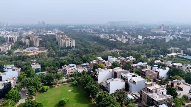 A drone view of Noida&rsquo;s residential belt shows factories, green buffers, and arterial roads fading into smog, highlighting rapid development under polluted skies.