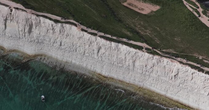 Aerial view of the stark contrast between the white cliffs and the turquoise sea, with a small boat visible below, Munxar Path, Marsaskala, Malta.