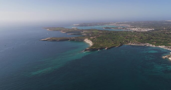 Aerial view of the rugged coastline meeting the turquoise sea, creating a stunning contrast near Munxar Path, Marsaskala, Malta.
