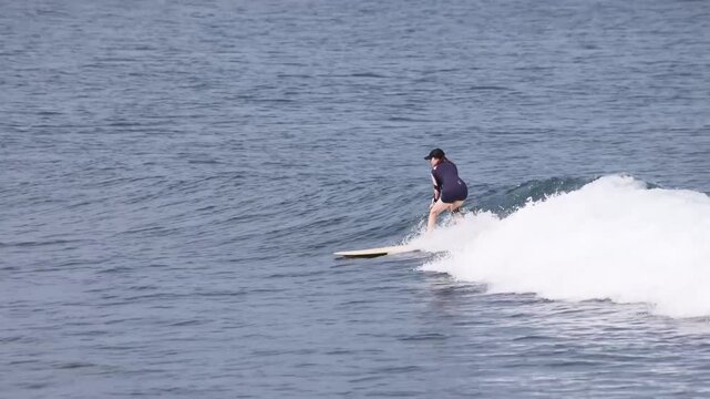 A female surfer surfs in the ocean on a summer day.
