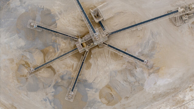 Aerial view of a symmetrical industrial landscape with conveyor belts radiating from a central hub amidst piles of raw materials, Robertson, Western Cape, South Africa.