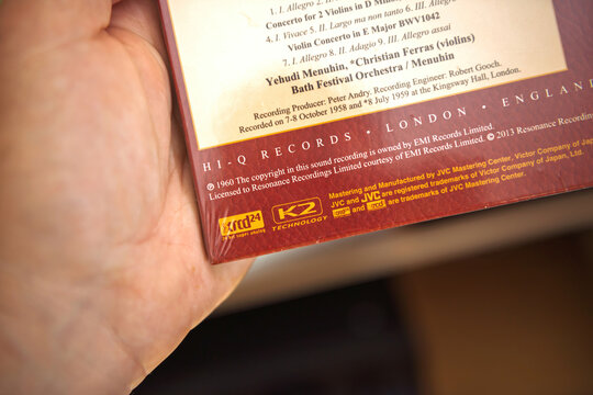 Paris, France - Sep 9, 2025: Closeup of a hand holding a sealed XRCD 24 classical music release showing mastering credits and K2 technology logos in a warm home audio environment