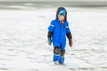 Junge spielt am winterlichen Strand in der Nordsee, hier Borkum