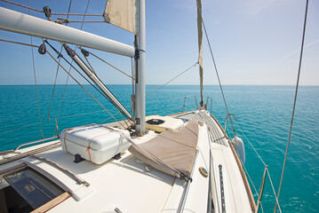 Landscape view from bow of luxury sailing boat yacht with detail of main mast and rigging showing blue ocean background