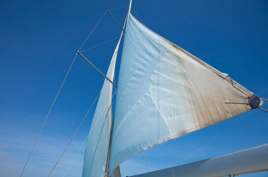 Closeup view of main sail with mast on luxury sailing yacht boat against a blue sky background