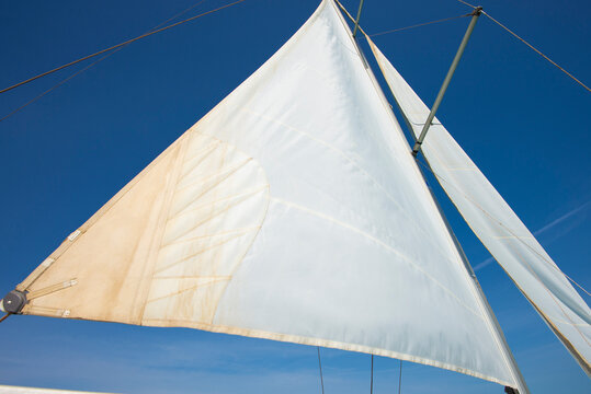 Closeup view of main sail with mast on luxury sailing yacht boat against a blue sky background