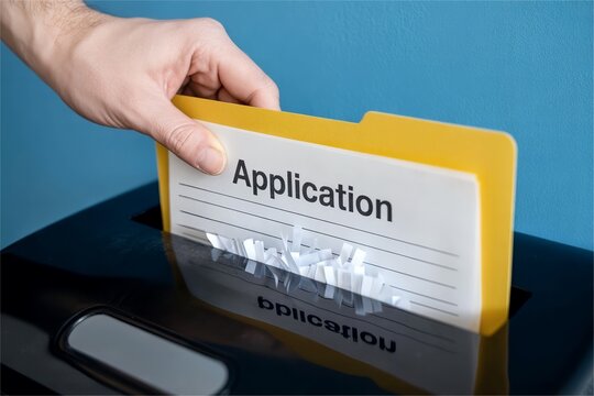 Job application document in shredder slot. Recruitment rejection