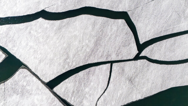 Aerial view of stark white ice floes fractured by dark, frigid waters, creating a mesmerizing geometric pattern. Superior, Wisconsin, USA.