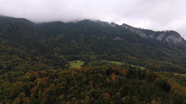 Explore the beauty of autumn in Bavaria with this drone flight over Aschau im Chiemgau. The Chiemgau Alps are shrouded in mist, revealing vibrant fall colors and high rocky mountain summits.