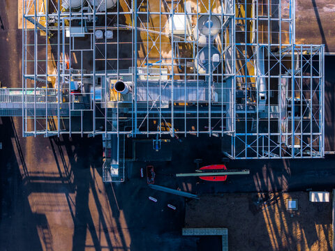 Aerial view of an industrial complex with structural steel framework casting shadows on the dark ground, La Roche-Jaudy, Brittany, France.