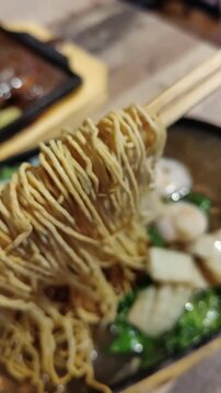 Top view of hard noodle on chopsticks served with sizzling vegetables