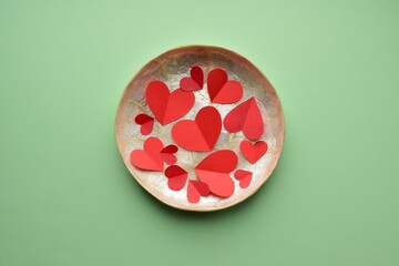 Plate with red paper hearts on a green background