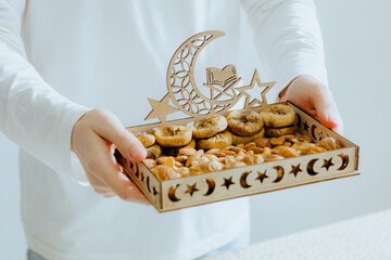 A young man holds out a Ramadan tray with dried fruits and nuts.