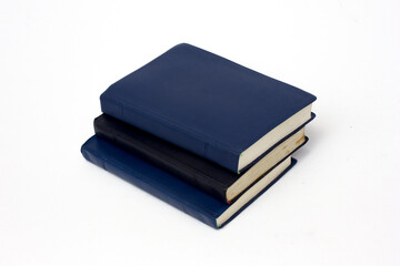 A stack of books with plain black and blue synthetic leather covers, isolated on white background.