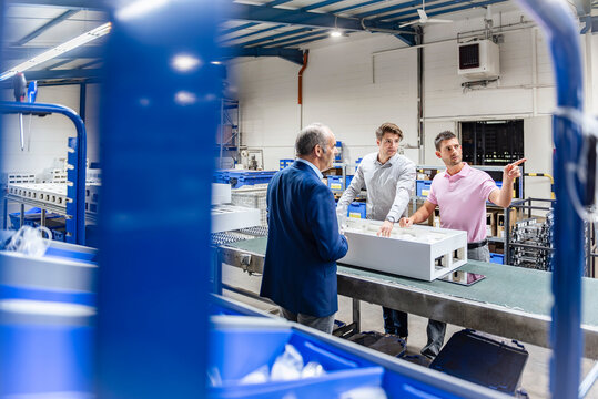 Team meeting in production hall discussing manufacturing process