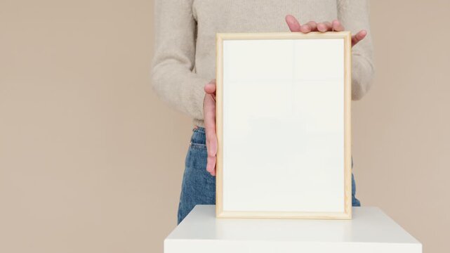 Woman holding blank wooden picture frame on white table